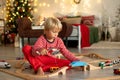 Cute blond child in pajama, playing at home on Christmas day with trains and railroad Royalty Free Stock Photo