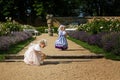 Cute blond curly twin girls dressed up as princesses in the garden of ancient castle, beautiful small girls in blue and pink long