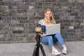 Cute blond female blogger with laptop recording video