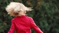 Cute blond girl is tyding her curly hair.