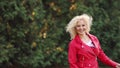 Cute blond girl is tyding her curly hair.