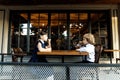 Cute blond guy and pretty girl, school years, dressed in school uniform, spends her time in the summer cafe on the street