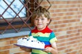 Cute blond kid boy holding big birthday cake. Happy smiling child celebrating birthday Royalty Free Stock Photo