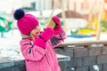 Cute blond kid girl holding smartphone and streaming for social networks winter fun activities at playground outdoor. Funny Royalty Free Stock Photo