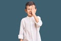 Cute blond kid wearing elegant shirt covering one eye with hand, confident smile on face and surprise emotion Royalty Free Stock Photo