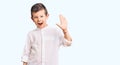 Cute blond kid wearing elegant shirt waiving saying hello happy and smiling, friendly welcome gesture