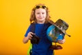 Cute blond kid wearing explorer hat and backpack on studio. Child explorer and adventure concept. Kid tourists hold