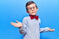 Cute blond kid wearing nerd bow tie and glasses clueless and confused expression with arms and hands raised Royalty Free Stock Photo