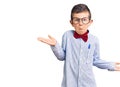 Cute blond kid wearing nerd bow tie and glasses clueless and confused expression with arms and hands raised Royalty Free Stock Photo