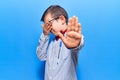 Cute blond kid wearing nerd bow tie and glasses covering eyes with hands and doing stop gesture with sad and fear expression Royalty Free Stock Photo