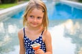 Cute blond little girl in blue swimsuit sitting at the swimming pool, holding passion fruit. Enjoy eating tropical fruit. Summer Royalty Free Stock Photo