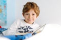 Cute blond little kid boy in pajamas reading book in his bedroom Royalty Free Stock Photo