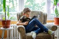 Cute blond little kid boy reading magazine in domestic room. Royalty Free Stock Photo