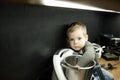 Cute blond little toddler boy mix food with hand in steel blender, food processor, sitting on kitchen drawer. Copy space Royalty Free Stock Photo