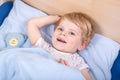Cute blond toddler boy in bed