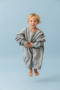 Active jumping toddler boy in a huge oversized grey longsleeve over blue