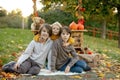 Cute blond toddler child and sibling brothers, standing next to autumn wooden stand with decoration, apples, leaves, mug,