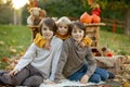 Cute blond toddler child and sibling brothers, standing next to autumn wooden stand with decoration, apples, leaves, mug,