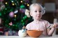 Cute blond toddler girl with blue eyes having her meal in christmas entourage Royalty Free Stock Photo