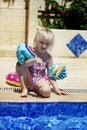 Cute blond toddler girl wearing armbands standing near the pool in a summer day Royalty Free Stock Photo