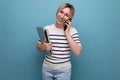 cute blond woman talking on the phone holding a laptop in her hands on a blue background with copy space Royalty Free Stock Photo