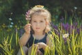 Cute blond young girl child stylish dressed in blue jeans dress posing on meadow of forest wild mayweed.Adoreable scene Royalty Free Stock Photo