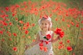 Cute blond young girl child stylish dressed in white handmade hooked dress wearing airy hat top posing on meadow of forest poppy p Royalty Free Stock Photo