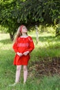 Cute blond young girl posing in a russian traditional red dress near fir tree Royalty Free Stock Photo