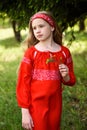 Cute blond young girl posing in a russian traditional red dress near fir tree Royalty Free Stock Photo