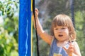 Cute blonde baby girl jumps on a trampoline on a sunny summer day. A little active girl plays in the fresh air on the playground, Royalty Free Stock Photo