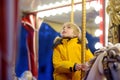 Cute blonde boy enjoying Christmas fair. Little child riding on a vintage carousel merry go round. Outdoors entertainment Royalty Free Stock Photo