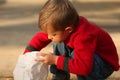 Cute blonde boy reaches into bag Royalty Free Stock Photo