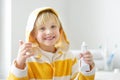 Cute blonde caucasian boy applying cream on his face in bathroom in the morning. Kids care cosmetics. Hygiene for child