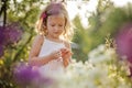 Cute blonde child girl in blooming summer garden