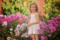 Cute blonde child girl playing in summer blooming garden