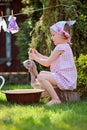 Cute blonde child girl plays toy wash in summer garden Royalty Free Stock Photo