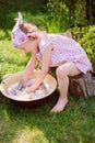 Cute blonde child girl plays toy wash in summer garden Royalty Free Stock Photo