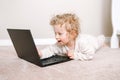 Cute blonde curly toddler baby boy working on laptop. Little kid child using technology. Early age education and development. Royalty Free Stock Photo