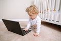 Cute blonde curly toddler baby boy working on laptop. Little kid child using technology. Early age education and development. Royalty Free Stock Photo