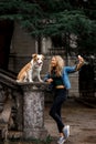 Cute blonde Girl in cool jeans jacket take a selfie in park with her dog, border collie Royalty Free Stock Photo