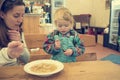 Cute blonde girl eating beef noodle soup in a restaurant with her mother. Royalty Free Stock Photo