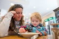 Cute blonde girl eating beef noodle soup in a restaurant with her mother. Royalty Free Stock Photo