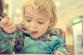 Cute blonde girl eating beef noodle soup in a restaurant with her mother. Royalty Free Stock Photo