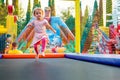 Cute blonde girl jumping on big trampoline at outdoor playground. Royalty Free Stock Photo