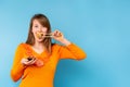 Cute blonde girl eating sushi roll with soy sauce, isolated on blue with side empty space. Smiled woman wearing orange Royalty Free Stock Photo