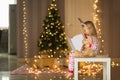 Cute blonde girl 5 years old, sitting near Christmas tree with teddy bear and reading book. Bedroom decorated with Christmas Royalty Free Stock Photo