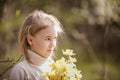 Cute blonde happy little girl with yellow daffodils in the spring country Royalty Free Stock Photo