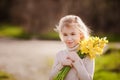 Cute blonde happy little girl with yellow daffodils in the spring country Royalty Free Stock Photo