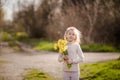 Cute blonde happy little girl with yellow daffodils in the spring country Royalty Free Stock Photo