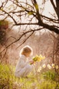 Cute blonde happy little girl with yellow daffodils in the spring country Royalty Free Stock Photo